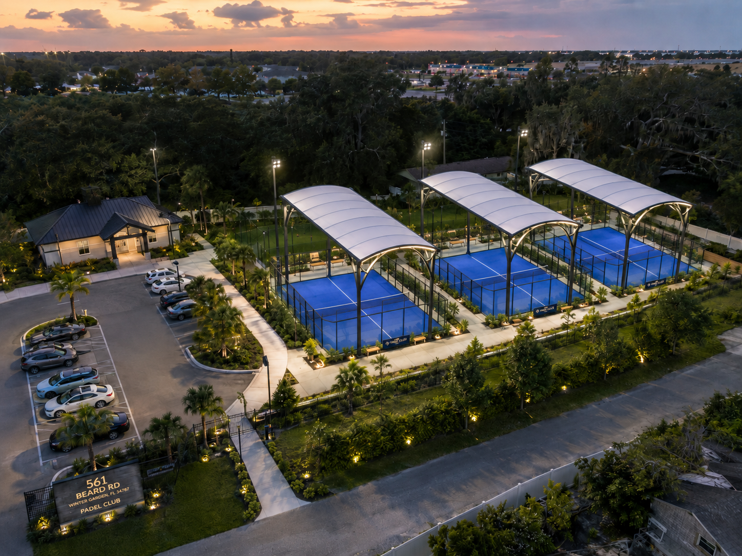 Aerial view of Padel Republic club at sunset — three canopied courts, parking, and clubhouse